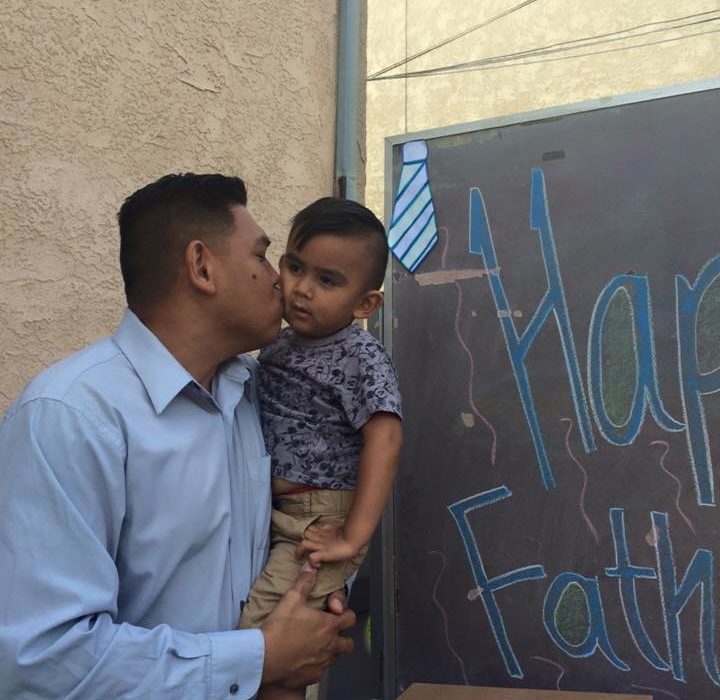 Man kissing young boy by Father's Day sign